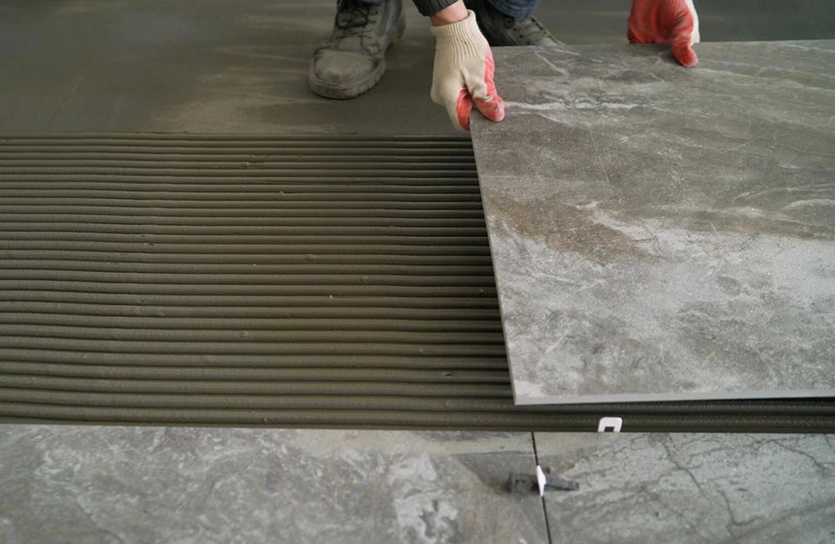 Laying floor tiles onto adhesive